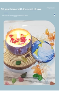 Detailed close-up of a burning scented candle with dried flower petals in a colorful tin