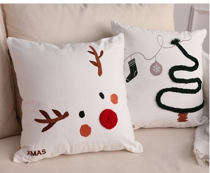 Detailed view of white cotton-linen Christmas cushion with reindeer embroidery on a sofa