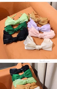 Close-up of assorted satin bow headbands in various colors on a warm fabric background