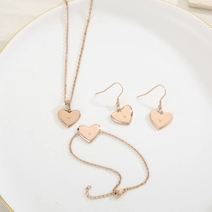 Parure de bijoux cœur en or rose avec collier, bracelet et boucles sur une assiette