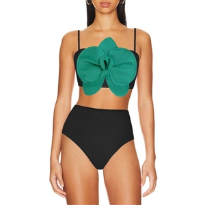Detail eines schwarzen Bikinis mit großer grüner 3D-Orchideenblüte am Oberteil
