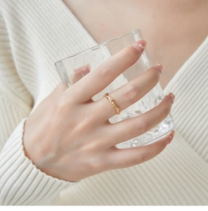 Close-up of a minimalist golden twig-shaped honeycomb ring with realistic bark texture