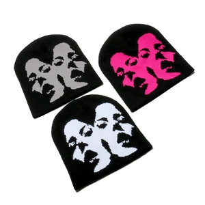 Three knit beanies with face profile patterns in pink, grey and white on black fabric