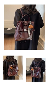 Detail of dark red glossy leather backpack with plush charm and polished texture
