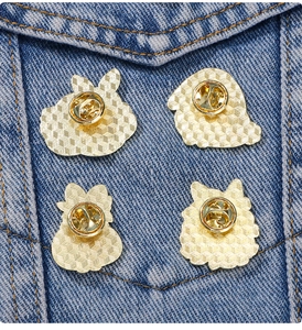 Detail of four golden rabbit enamel pins with butterfly clutch backs on denim jacket