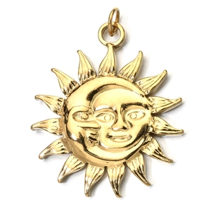 Macro detail of a golden vintage sun and crescent moon face pendant with metallic luster