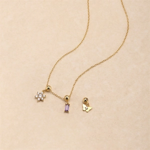 Macro shot of gold necklace with zircon flower, purple gem, and butterfly pendants