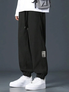 Detailed view of black corduroy cargo pants featuring embroidered text patch and ribbed cuffs