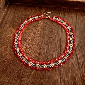 Macro detail of hand-woven red glass bead necklace with intricate ethnic wave pattern