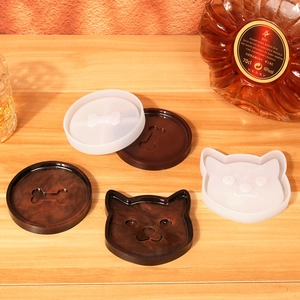 Silicone coaster mold set with cat and bone shapes on wooden table with wine accessories