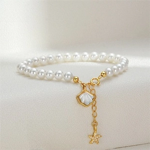 Close-up of S925 silver pearl bracelet with golden shell and starfish charms