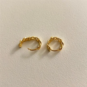 Close-up of golden 925 silver hoop earrings with chain link texture on beige surface