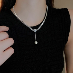 Dettaglio di una collana a Y in argento con zirconi incastonati e una perla bianca tonda