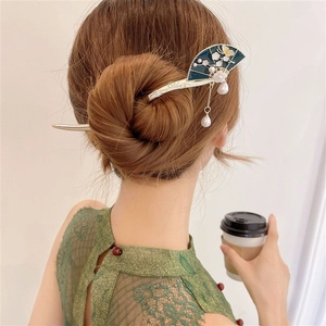 Detail of a fan-shaped hair stick with blue enamel patterns and pearl tassels on a bun
