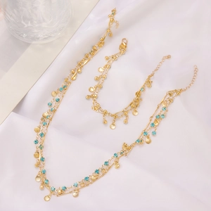 Macro detail of layered gold necklace with shell charms and blue crystal on white silk