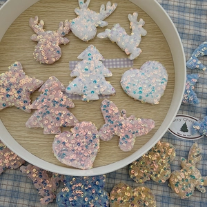 Close-up of glitter fabric Christmas shapes like trees and stars on a wooden tray