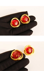 Detail of vintage red resin earrings with gold leaf accents and spiral metal frame