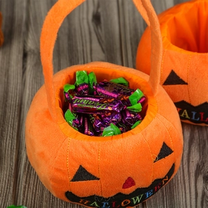 Detail of plush orange Halloween pumpkin candy bag with black embroidery and handle