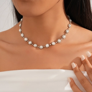 Close-up of sparkling silver flower necklace with rhinestone petals on a model