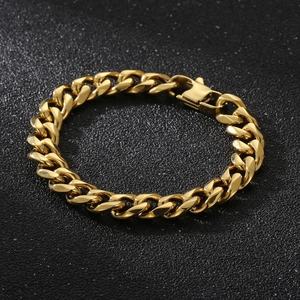 Détail d'un bracelet gourmette en acier inoxydable doré avec fermoir mousqueton sur fond noir