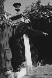 Dramatic fashion shot of long faux leather coat with fur collar and belted waist detail