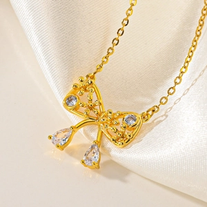 Macro shot of gold bow-knot necklace with sparkling zircons and teardrop pendants