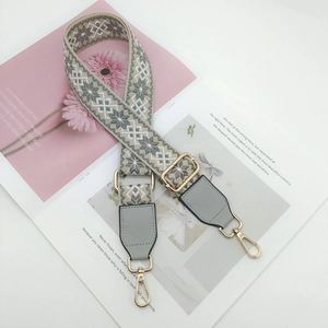 Detail of adjustable geometric snowflake jacquard bag strap with gold metal buckles