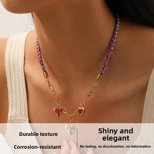 Détail du collier tressé rose et bleu avec chaîne dorée et pendentifs en cœur diamanté