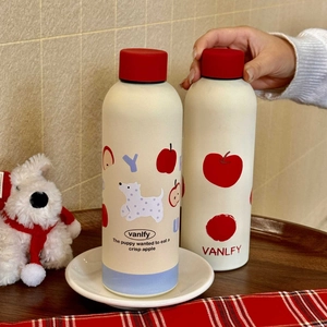 Detail of cream vacuum flask with red lid featuring cute dog and apple patterns