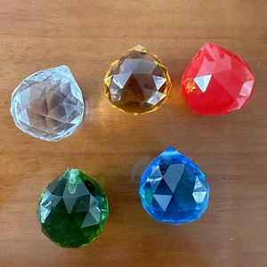 Faceted crystal chandelier prisms in clear, amber, red, green, and blue on a wooden table