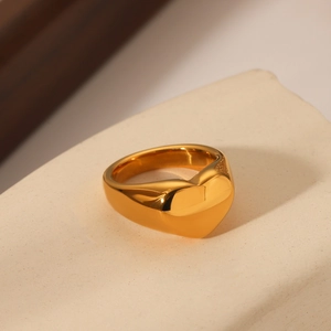 Detailed view of wide 18K gold plated heart ring on stone surface with mirror finish