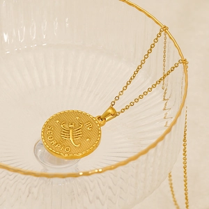 Detail of 18k gold Scorpio zodiac pendant necklace draped on art glass bowl