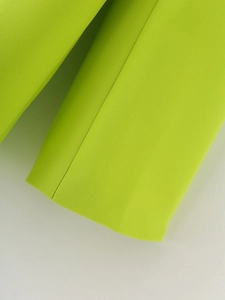 Gros plan détaillé montrant les coutures précises et la texture de la manche du blazer vert néon