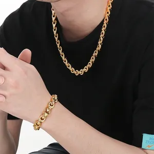 Close-up of a gold chunky twist chain necklace and bracelet set worn by a male model