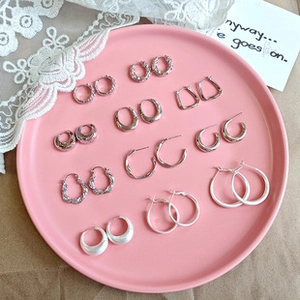 Detailed collection of vintage silver earrings displayed on a pink tray with lace