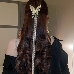 Détail de pince à cheveux papillon dorée avec de longs glands sur les cheveux