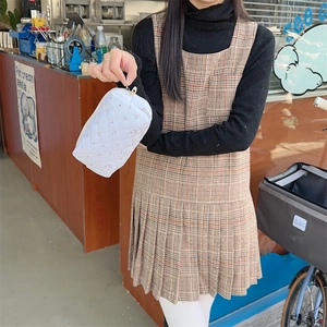Quilted white cosmetic bag with cherry patterns held by a model in a cozy cafe