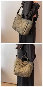 Detail of olive green quilted tote bag featuring a side zipper pocket and adjustable strap
