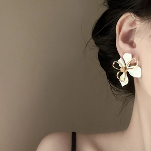 Close-up of elegant double-layered white flower earrings on model with gold floral center