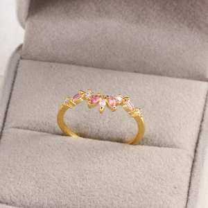 Détail d'une bague dorée avec zircons marquise roses et blancs dans un écrin en velours