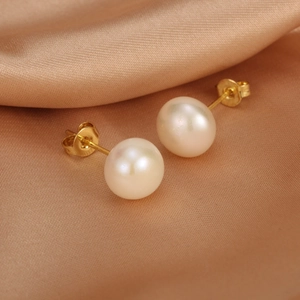 Detailed macro view of white freshwater pearl earrings on elegant champagne silk fabric