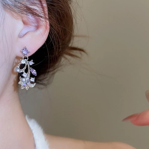 Close-up of model wearing purple flower and leaf drop earrings with sparkling crystals