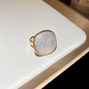 Vue macro d'une bague dorée ornée d'une pierre nacrée blanche irrégulière à texture marbrée