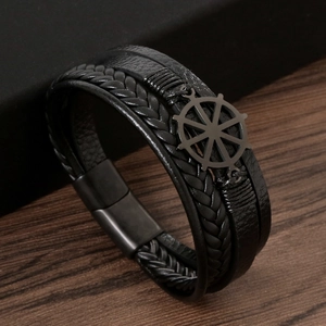 Detail of multi-layer black leather bracelet with steel rudder charm on wood surface