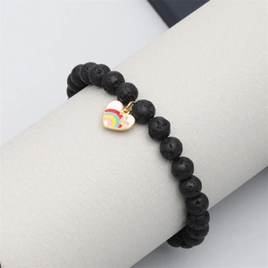 Lava rock bracelet with colorful enamel heart charm on jewelry display stand