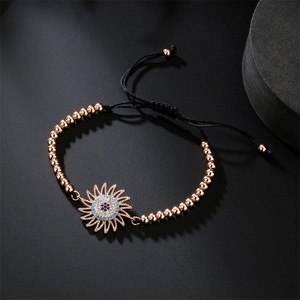 Detail of rose gold beads and evil eye sunflower charm on black woven adjustable bracelet
