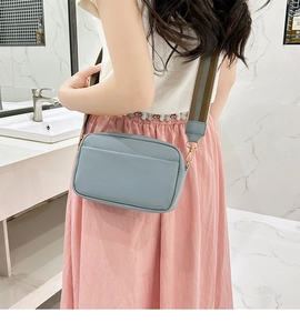 Close-up of light blue lychee pattern crossbody bag with striped wide shoulder strap