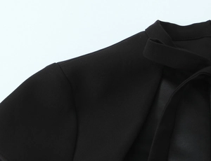 Close-up of black polka dot dress featuring a stylish bow tie and fine fabric texture