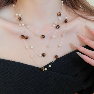Détail du collier doré multi-rangs avec perles œil de tigre brunes et perles blanches