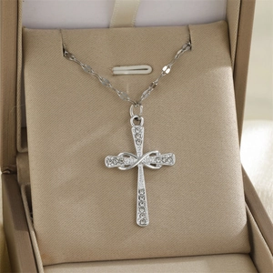Collier croix infini en argent avec zircons brillants dans un coffret à bijoux beige